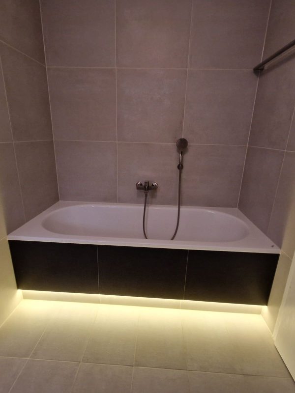 Baignoire encastrée dans un socle carrelé avec bandeau LED