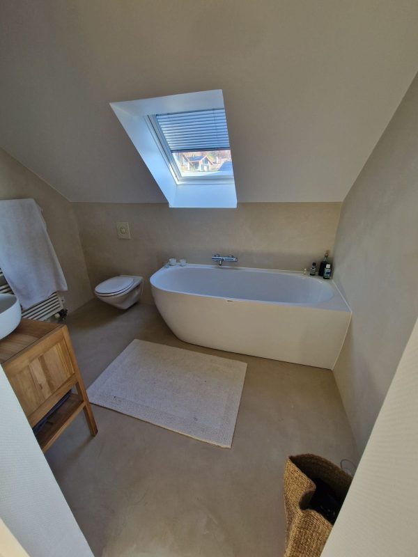Baignoire d'angle installée sous une pente de toit avec fenêtre de toit