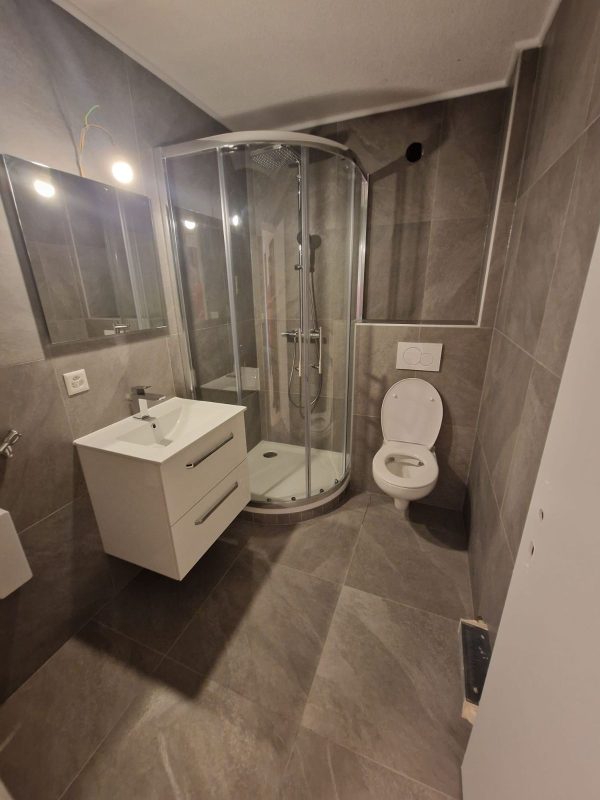 Salle de bain complète avec douche d'angle vitrée, meuble vasque blanc et WC suspendu