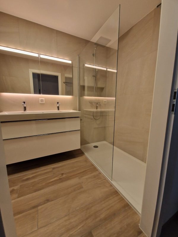 Douche à l'italienne et double vasque avec éclairage indirect, carrelage beige