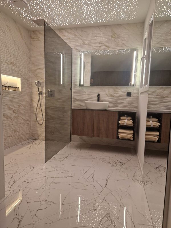Douche à l'italienne carrelée en marbre grand format avec meuble vasque en bois